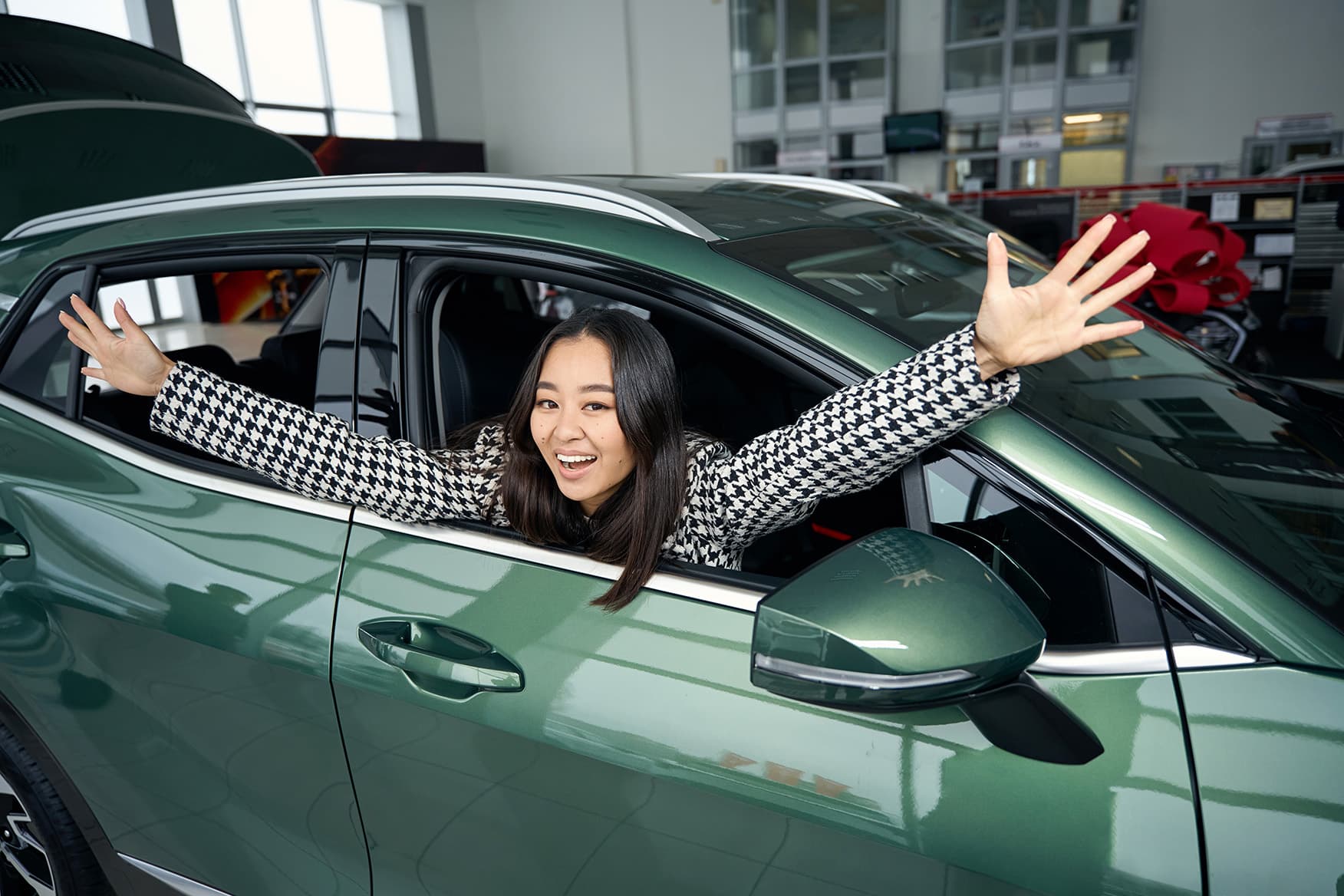 A delighted customer waving from the window of her new SUV